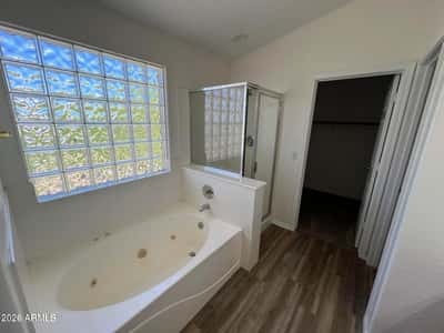 Enjoy a spa-like atmosphere with a soaking tub, separate shower, and natural light filtering through decorative glass block windows. A relaxing retreat within the primary suite.