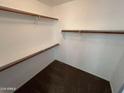 Large walk-in closet with multiple hanging rods and abundant storage capacity. Perfect for organizing clothing, accessories, and seasonal items with ease.