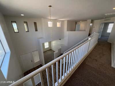 Open upper hallway featuring attractive architectural elements and views of the home's soaring entryway. This flexible space contributes to the home's open-concept design.