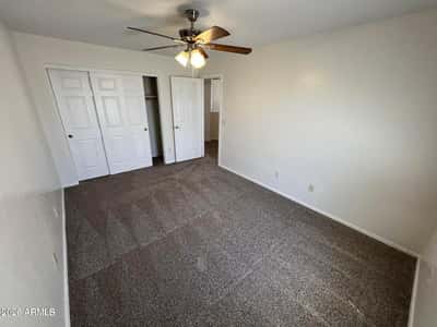 Secondary bedroom featuring soft carpeting, ceiling fan, closet storage, and natural light. The clean, neutral design allows for easy personalization.