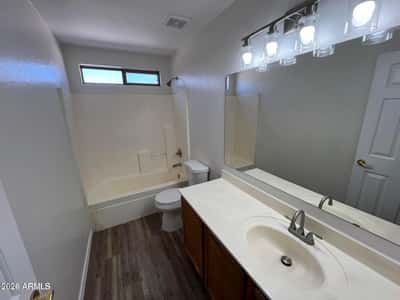 Bright full bathroom offering a tub and shower combination, updated lighting, generous vanity space, and durable flooring. Conveniently located near the upstairs bedrooms.