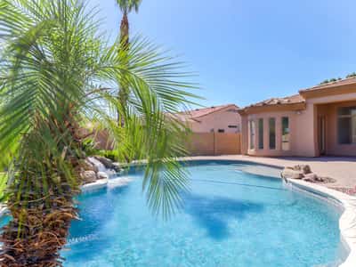 A sparkling pool with a cascading rock waterfall, mature palm trees, paver patio, and private backyard creates an exceptional outdoor retreat. Perfect for enjoying the Glendale lifestyle year-round.