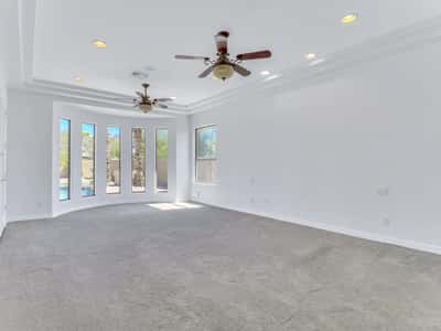 The spacious owner's suite offers tray ceilings, plush carpeting, ceiling fans, expansive windows, and plenty of room for a sitting area. A relaxing retreat within this beautifully maintained Glendale home.