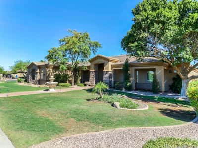Attractive front exterior highlighted by stone detailing, lush landscaping, covered front porch, mature trees, and exceptional curb appeal in a desirable Glendale neighborhood.