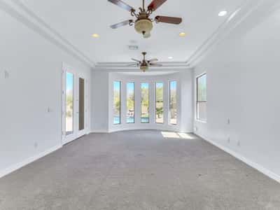 Spacious owner's suite offering a tray ceiling, abundant natural light, backyard views, and private patio access. This serene retreat provides the perfect place to unwind at the end of the day while enjoying the comfort of this custom Glendale home.