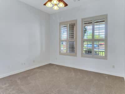 Plantation shutters, soft carpeting, high ceilings, and generous natural light make this secondary bedroom ideal for guests, family, or a home office. A flexible living space within this Glendale residence.