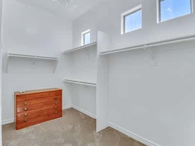 The spacious owner's closet offers custom shelving, built-in drawers, multiple hanging sections, and high ceilings that create a bright and functional storage area within this Glendale property.