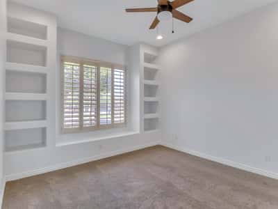 This inviting bedroom features plantation shutters, built-in shelving, plush carpeting, soaring ceilings, and abundant natural light. A flexible living space ideal for guests, family, or a private office in Glendale.