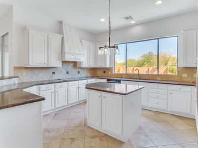 Beautifully designed kitchen with granite countertops, custom cabinetry, center island, decorative range hood, and expansive prep space. This Glendale home combines timeless style with exceptional functionality.