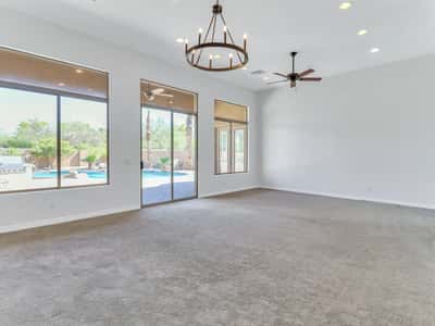 Spacious living room filled with natural light through oversized windows and sliding glass doors that frame beautiful backyard views. The open design enhances comfort while creating effortless indoor-outdoor living.