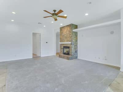 Elegant living area centered around a striking stone fireplace with an open floor plan that flows effortlessly into the kitchen. A warm and welcoming space designed for relaxing or entertaining guests.