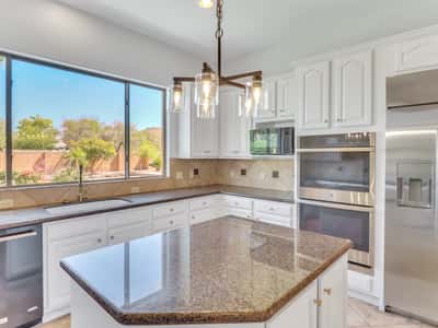 This bright kitchen features granite countertops, stainless steel appliances, a large center island, generous cabinetry, and a large window overlooking the beautifully landscaped backyard. A standout feature of this Glendale property.