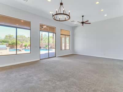 Spacious living area featuring high ceilings, recessed lighting, elegant chandelier, ceiling fan, and expansive glass doors opening directly to the backyard retreat in Glendale.