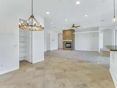 The open floor plan offers seamless flow between the dining area, kitchen, and family room with elegant lighting, recessed lighting, tile flooring, and a beautiful stone fireplace. A welcoming gathering space in this Glendale home.