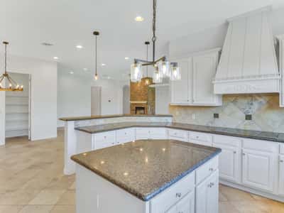 Decorative cabinetry, granite counters, a custom range hood, pendant lighting, and a raised breakfast bar create an elegant kitchen that opens effortlessly to the living areas of this Glendale home.