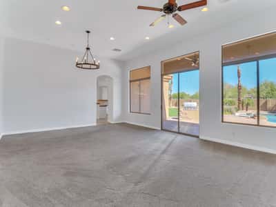 Open living room with soaring ceilings, abundant natural light, oversized windows, sliding glass doors, and seamless access to the covered patio and resort-style backyard in Glendale.