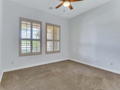 Inviting bedroom featuring plantation shutters, plush carpeting, ceiling fan, and bright natural light. This Glendale home offers comfortable guest accommodations with versatile living space.