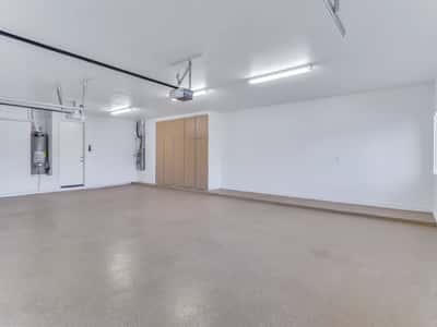 Finished three-car garage featuring epoxy flooring, built-in storage cabinets, bright lighting, and plenty of room for vehicles, tools, and recreational equipment. A practical and well-organized feature of this Glendale home.