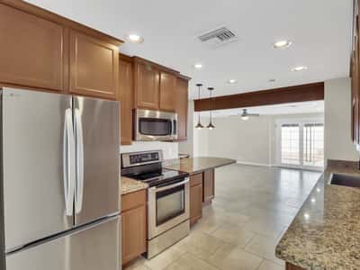 Modern kitchen showcases granite countertops, stainless steel appliances, extensive cabinetry, and an open-concept design that blends style with everyday functionality in this remodeled Phoenix rental.