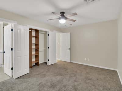Bright guest bedroom with neutral carpeting, ceiling fan, generous closet storage, and built-in shelving. This flexible living space adds comfort and functionality to this updated Phoenix rental.