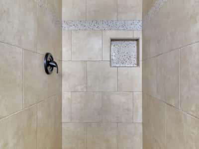 Elegant walk-in shower with oversized tile, mosaic accent band, recessed storage niche, and rainfall showerhead. This spa-inspired feature elevates the appeal of this updated Phoenix rental.