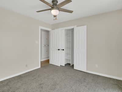Comfortable bedroom with soft carpeting, ceiling fan, ample closet storage, and neutral finishes. This inviting room provides flexibility for family, guests, or a home office in Phoenix.
