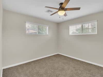 Bright bedroom offering plush carpeting, ceiling fan, dual windows, and neutral colors ready to fit your lifestyle. A versatile room in this move-in-ready Phoenix rental.