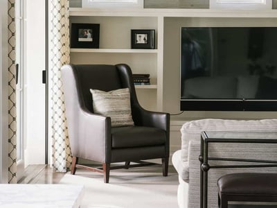 Stylish living room featuring a cozy armchair, modern decor, and abundant natural light from large windows.
