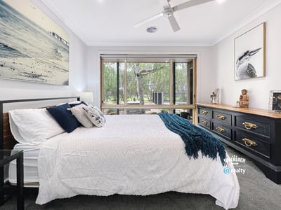 Spacious bedroom featuring large windows, natural light, and a view of lush outdoor greenery.