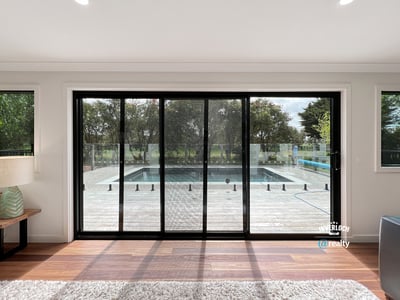 Bright and inviting living space with expansive glass doors opening to a private pool and outdoor deck.