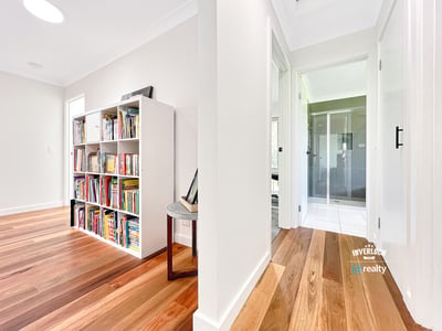 Bright and inviting interior featuring wooden floors, a spacious hallway, and a versatile bookshelf area.