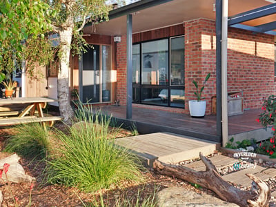 Contemporary home featuring expansive windows and an inviting outdoor space surrounded by lush greenery.