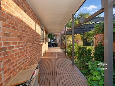 Inviting walkway lined with brick and greenery, leading to a secluded outdoor living space.