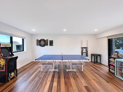 Bright recreational space featuring a ping pong table, arcade machine, and dartboard for entertainment.