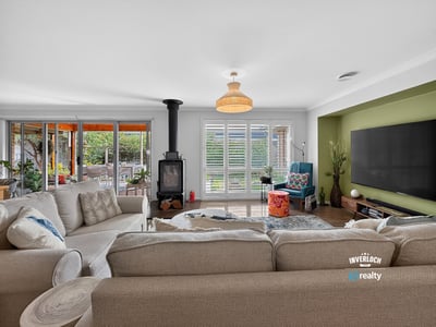 Spacious living area with a cozy stove, large windows, and bright natural light throughout.