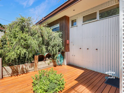 Bright and inviting outdoor space featuring a wooden deck, unique architectural details, and lush greenery.