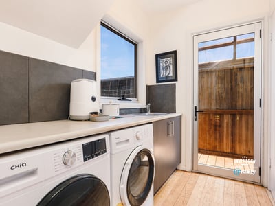 Bright laundry room featuring modern appliances and direct access to a private outdoor space.