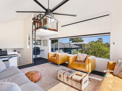 Bright and airy living space featuring unique shelving, cozy seating, and stunning outdoor views.