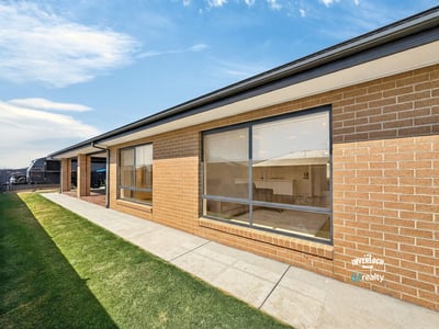 Modern brick home featuring large windows and a spacious yard, perfect for outdoor activities and natural light.