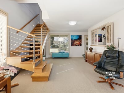 Spacious living area with inviting staircase and large windows offering ample natural light.
