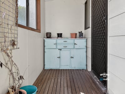 Bright and inviting enclosed porch featuring a rustic blue cabinet, perfect for additional storage and decor.
