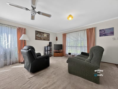 Spacious living room featuring large windows, comfortable seating, and a light-filled atmosphere, perfect for relaxation.