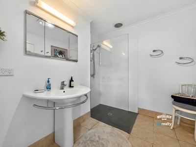 Modern bathroom featuring a glass shower, sleek fixtures, and ample natural light for a bright atmosphere.