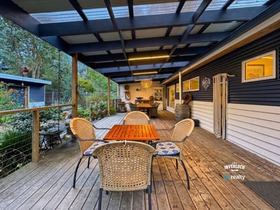 Spacious outdoor deck ideal for entertaining, featuring a cozy dining area and surrounding natural greenery.