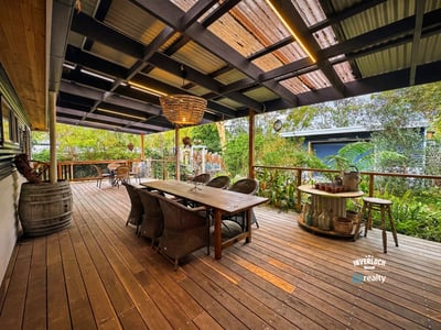 Spacious outdoor entertaining area featuring a large dining table, surrounded by lush greenery and a cozy atmosphere.