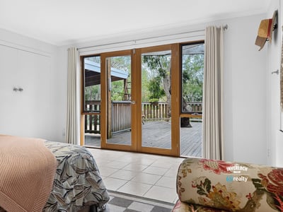 Bright and airy bedroom featuring sliding doors that open to a spacious deck surrounded by greenery.