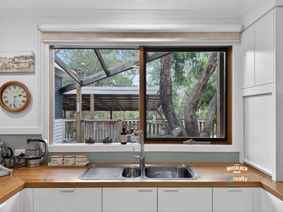 Bright kitchen featuring a large window that overlooks a spacious backyard with mature trees.