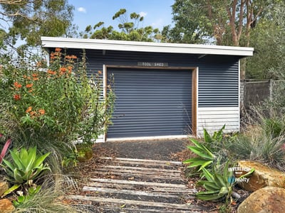 This functional tool shed offers practical storage solutions, surrounded by lush landscaping and natural beauty.