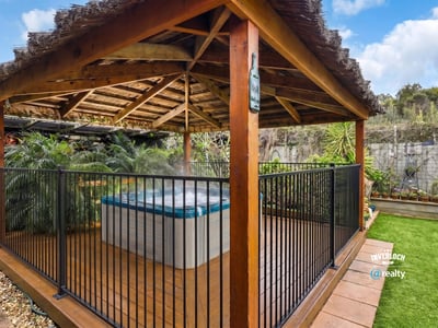 Relax in this private outdoor gazebo featuring a hot tub, surrounded by lush greenery.