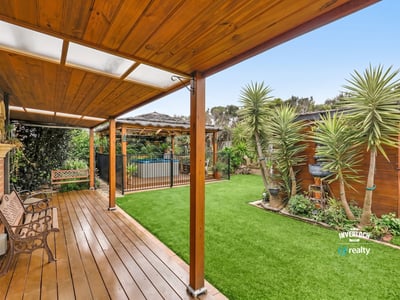 Discover a spacious outdoor oasis featuring sleek decking, vibrant greenery, and a refreshing pool area.